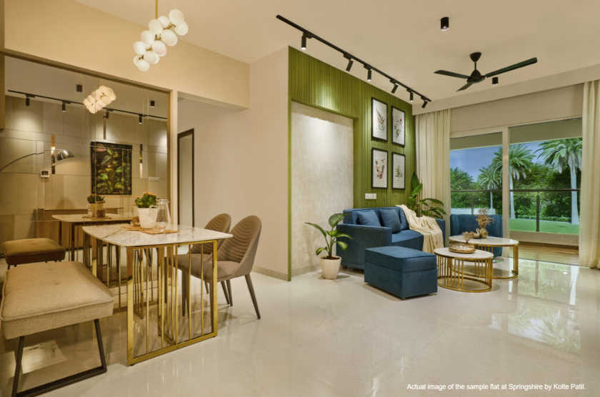 Light, minimalist living and dining space with soft beige tones and a cozy sofa facing lush greenery.